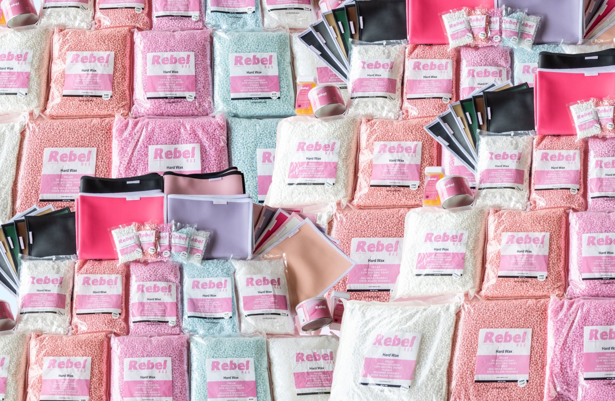 Photo of a stockpile of bags of Rebel hard wax beads for hair removal and bags of Rebel soft wax.