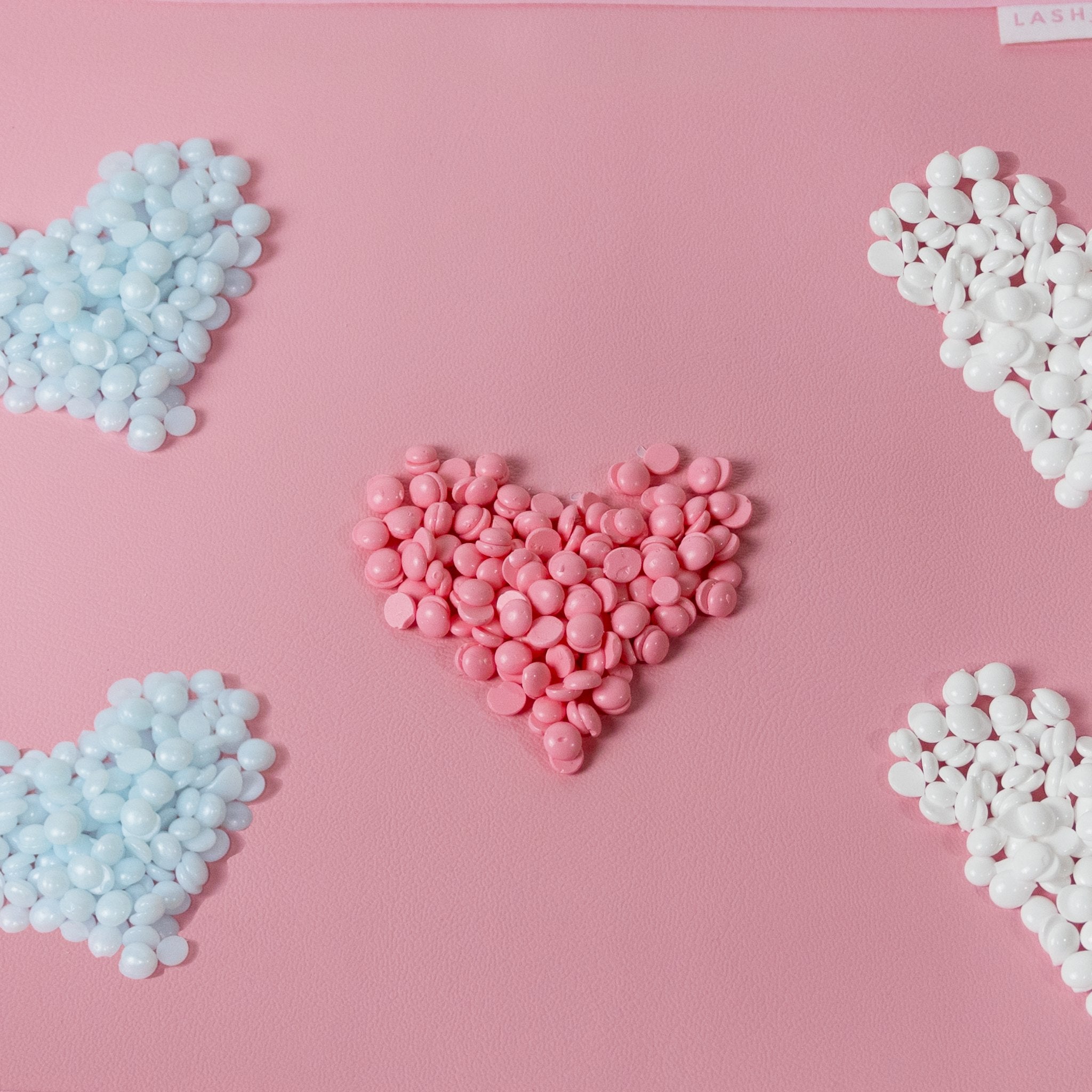 photo of pink, blue and white hearts made out of hard wax beads for hair removal.