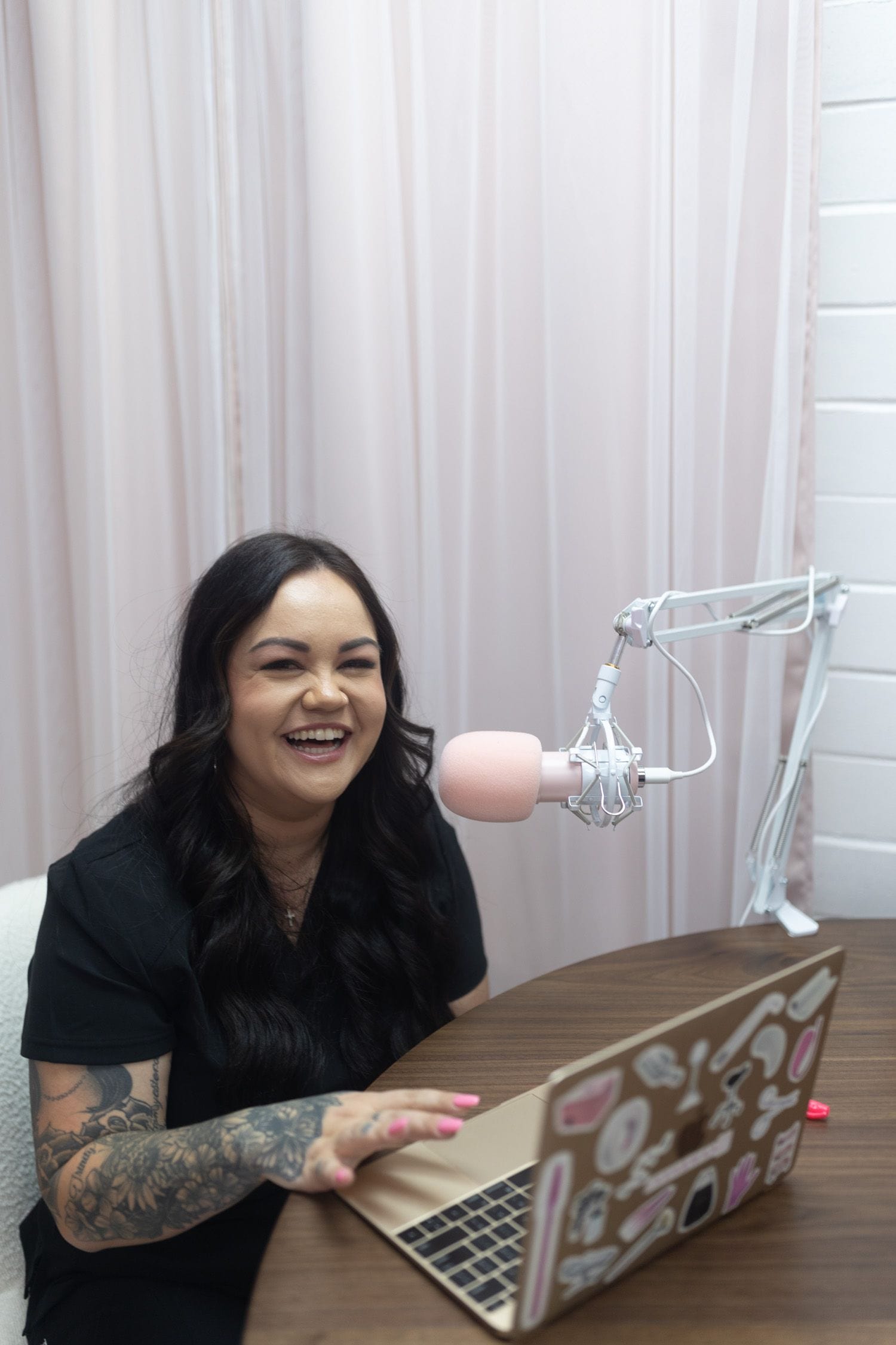 Photo of Bree owner of Lash and Wax OC laughing, sitting in front of her laptop, smiling while conducting an online waxing training in front of her laptop.