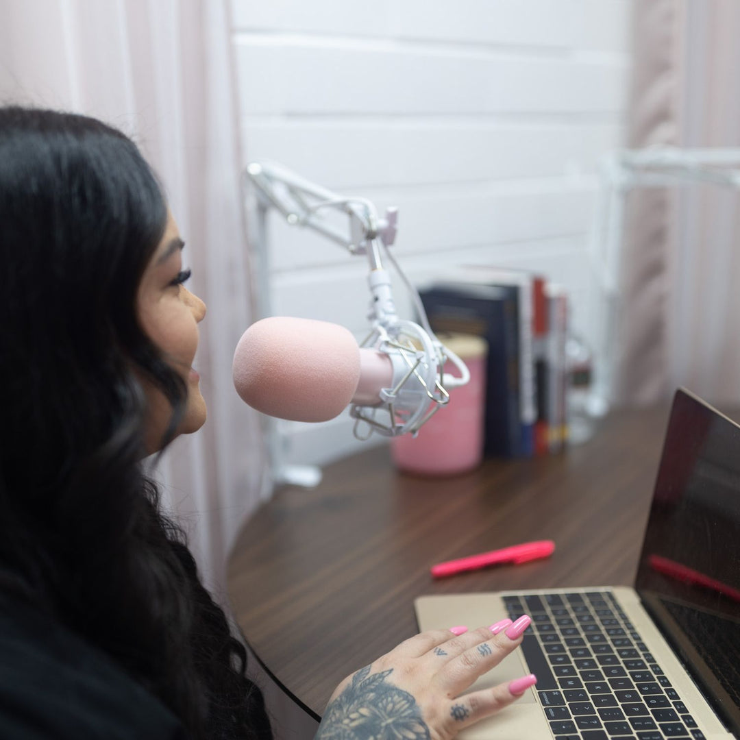 Photo of Bree owner of Lash and Wax OC in front of her laptop speaking into a microphone.